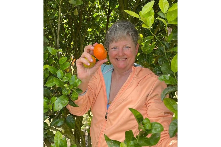 photo of Kristine Munoz holding up citrus among citrus trees