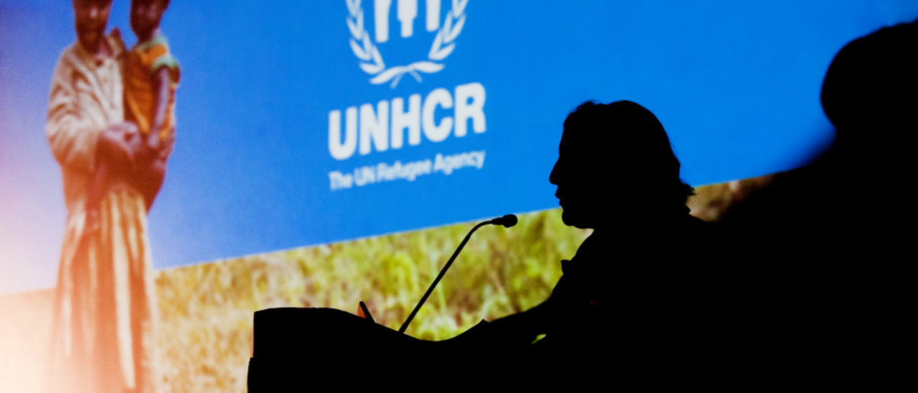 Speaker silhouette against UNHCR screen at GH conference